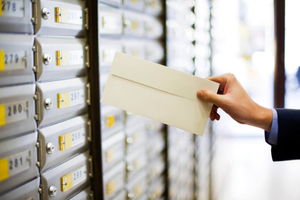 Close-up of hand placing mail in mailboxes